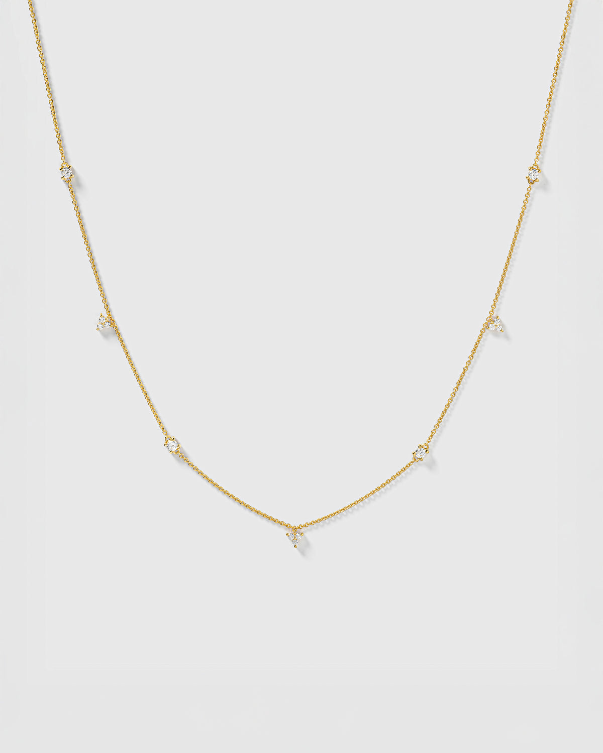 A product shot of the Celestia Necklace in gold, featuring a delicate chain with sparkling cubic zirconia stones set at intervals.