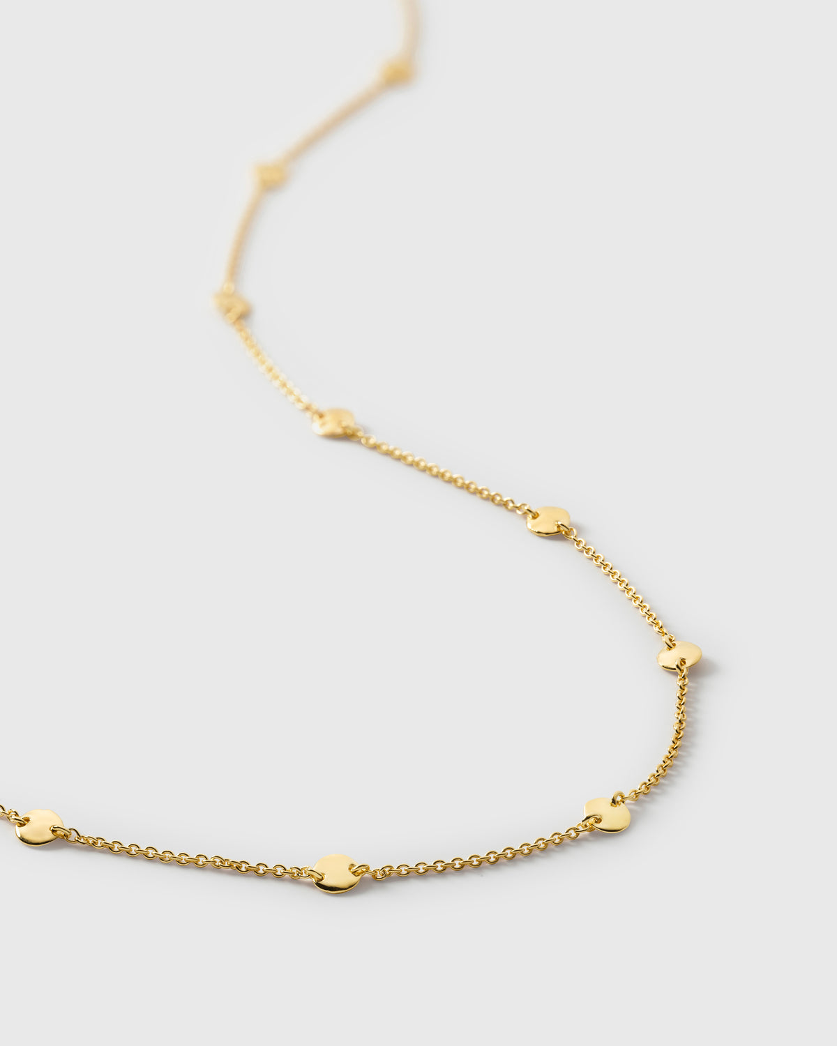 A close-up shot of the Solea Necklace in gold, highlighting the detail of its fine chain adorned with small, round, hammered circles.