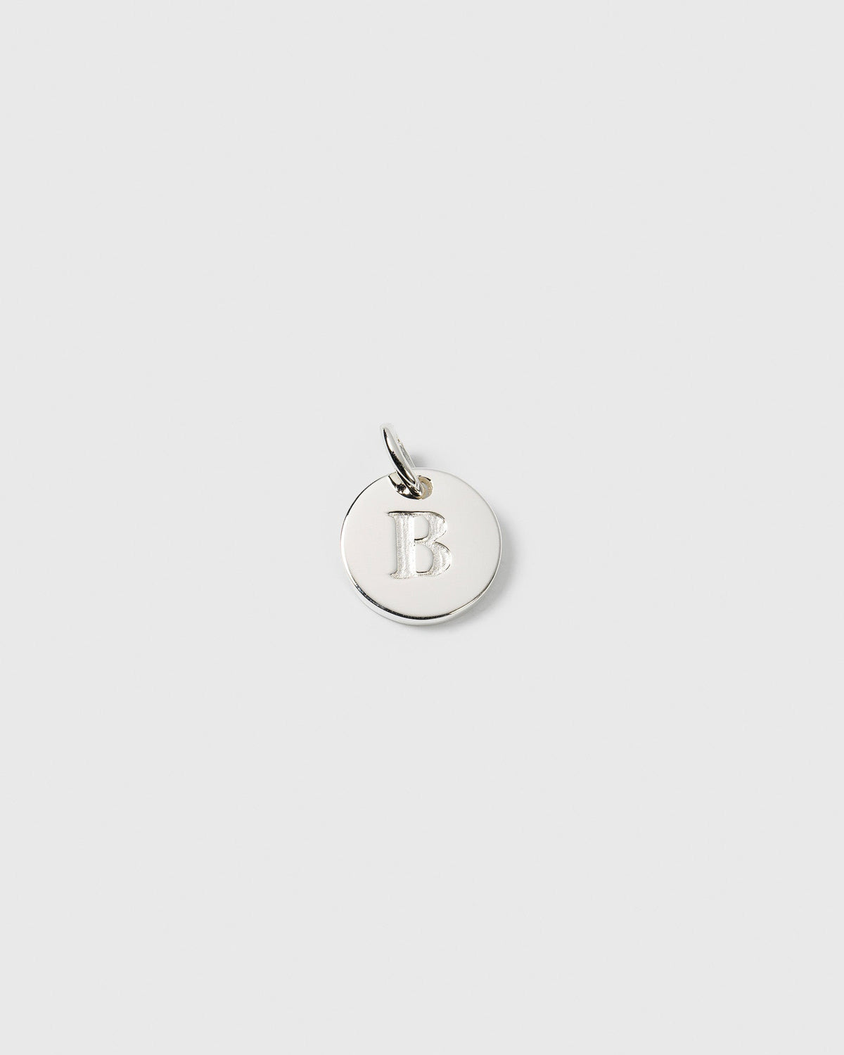 A product shot of the Syster P Beloved Mini Letter charm in silver, featuring the letter 'B' engraved on its small, round surface.