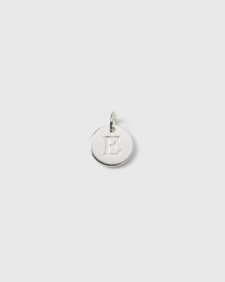 A product shot of the Beloved Mini Letter charm in silver, featuring the letter E engraved on its round surface.