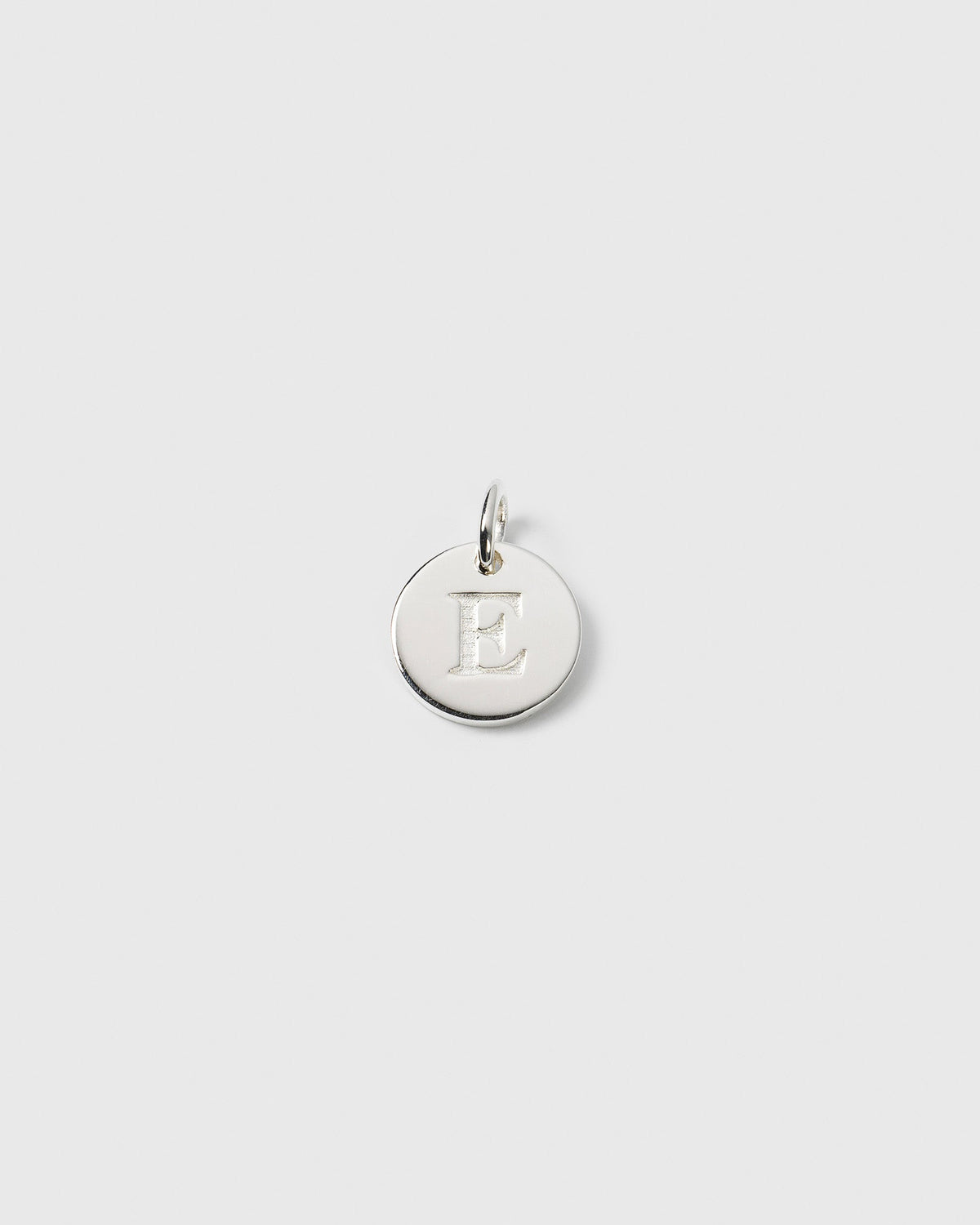 A product shot of the Beloved Mini Letter charm in silver, featuring the letter E engraved on its round surface.