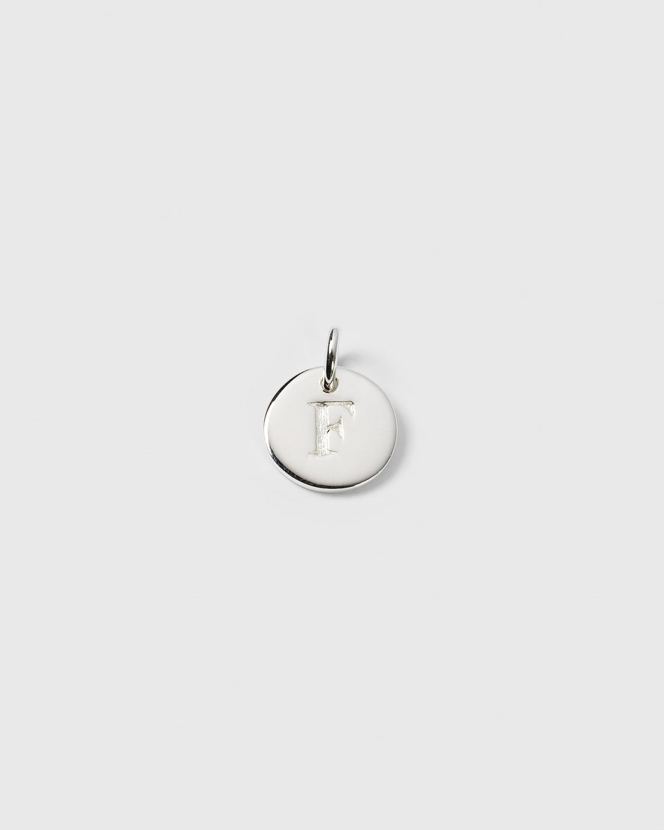 A product shot of the Beloved Mini Letter Silver pendant, showing the letter 'F' engraved on the small, round charm.