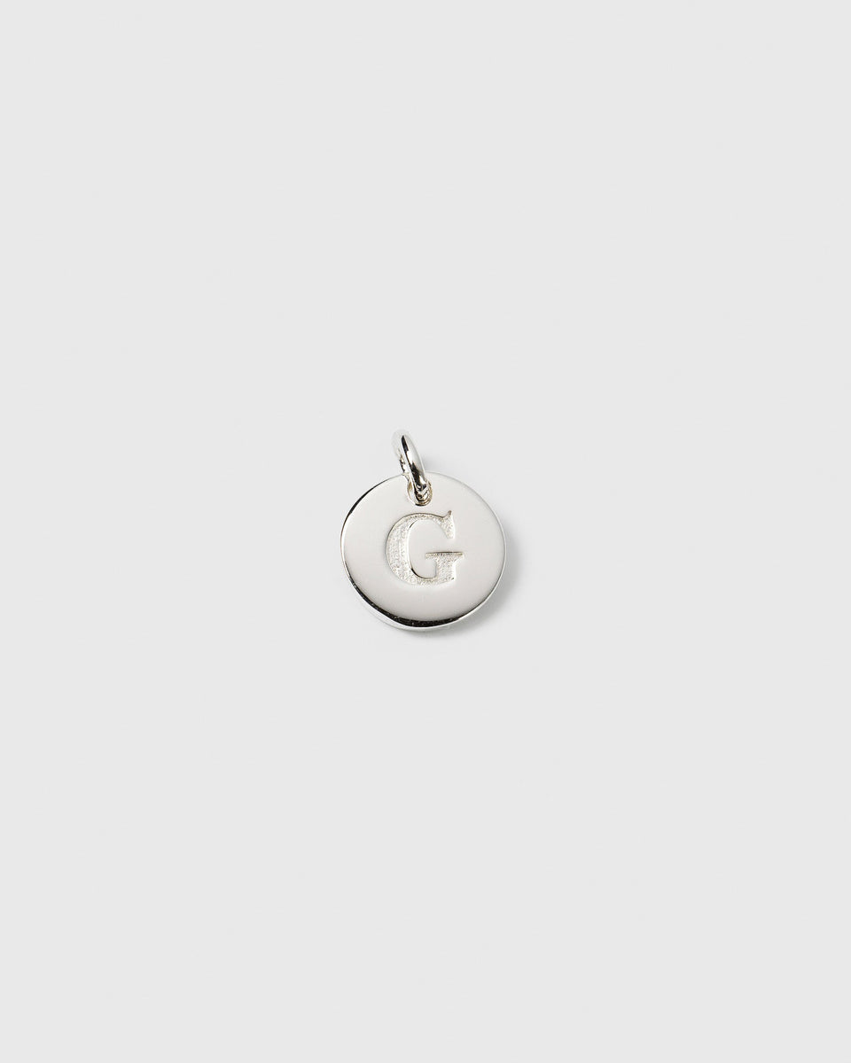 A product shot of the silver Beloved Mini Letter G pendant, showing the initial engraved on a small, circular charm.