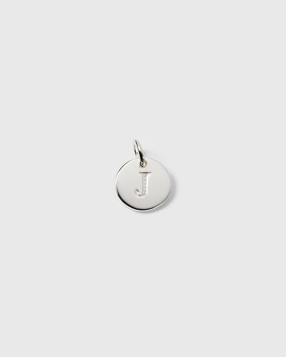 A product shot of the Beloved Mini Letter 'J' pendant in silver, a small circular charm with the initial engraved on the front.