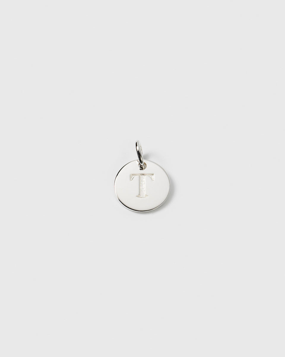 A product shot of the Beloved Mini Letter T pendant in silver, a small round charm with the letter T engraved on it.