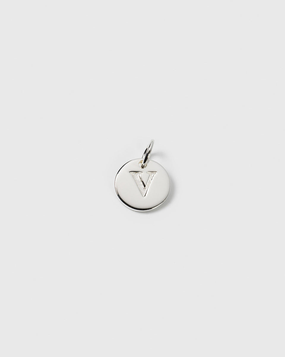 A product shot of the Beloved Mini Letter charm in silver, a small round pendant with the letter 'V' engraved on its surface.