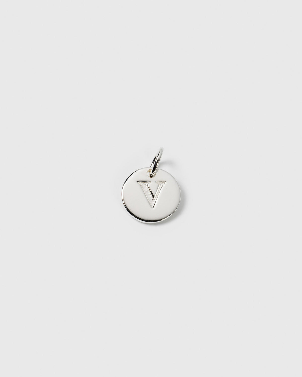 A product shot of the Beloved Mini Letter charm in silver, a small round pendant with the letter 'V' engraved on its surface.