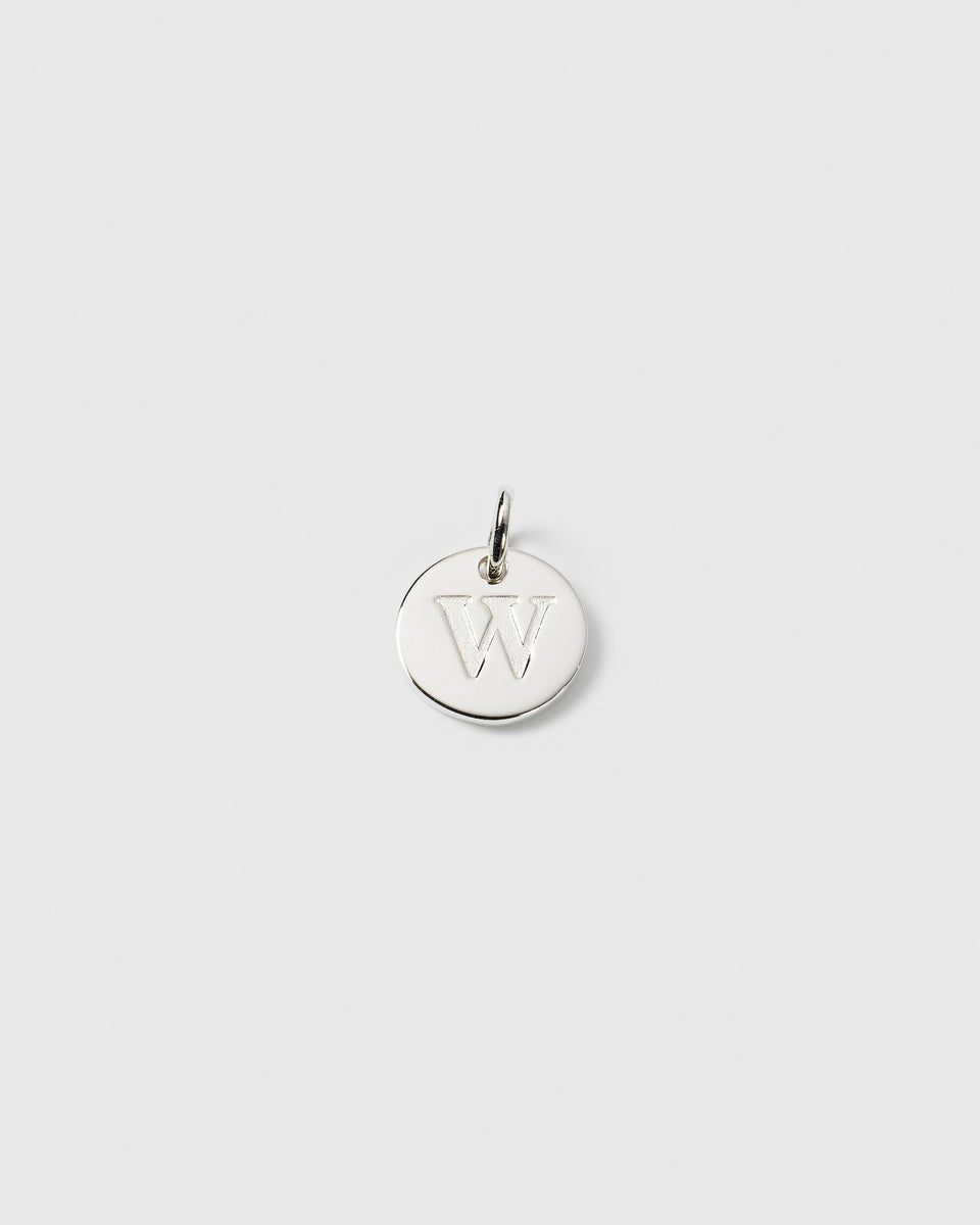 A product shot of the Beloved Mini Letter charm in silver, a circular pendant engraved with the letter W.