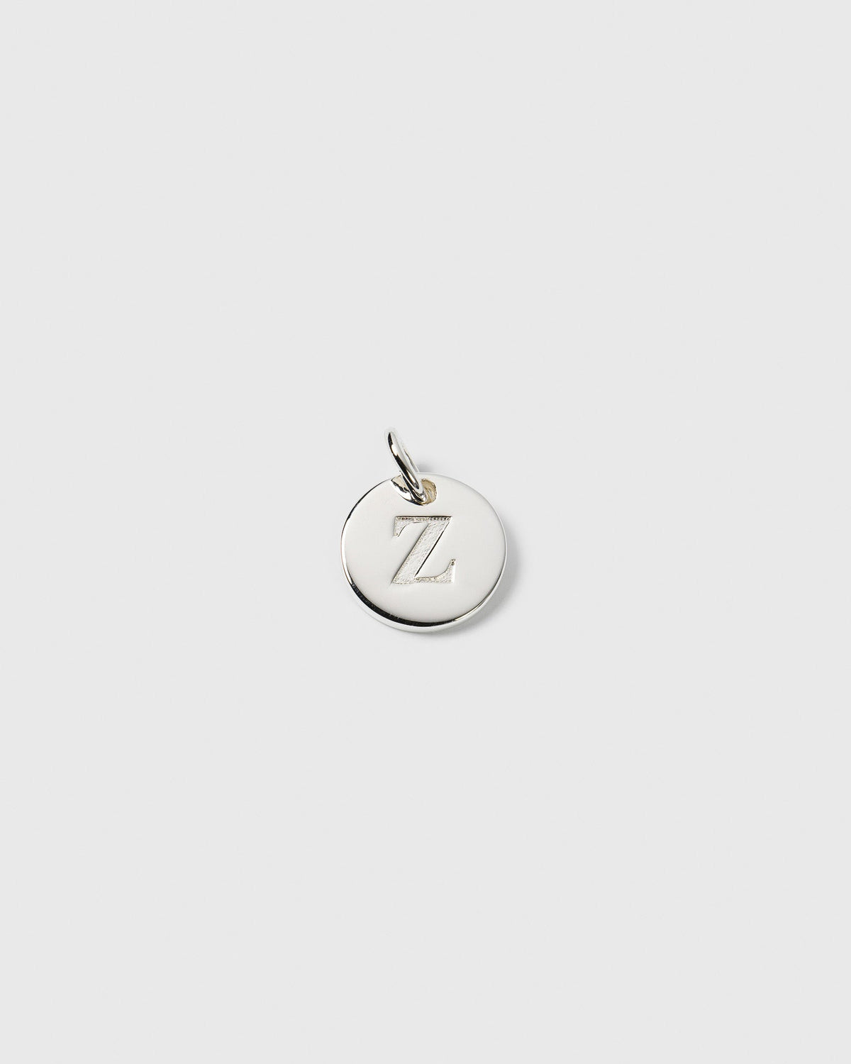 A product shot of the Beloved Mini Letter Silver charm, a small round pendant engraved with the letter Z.