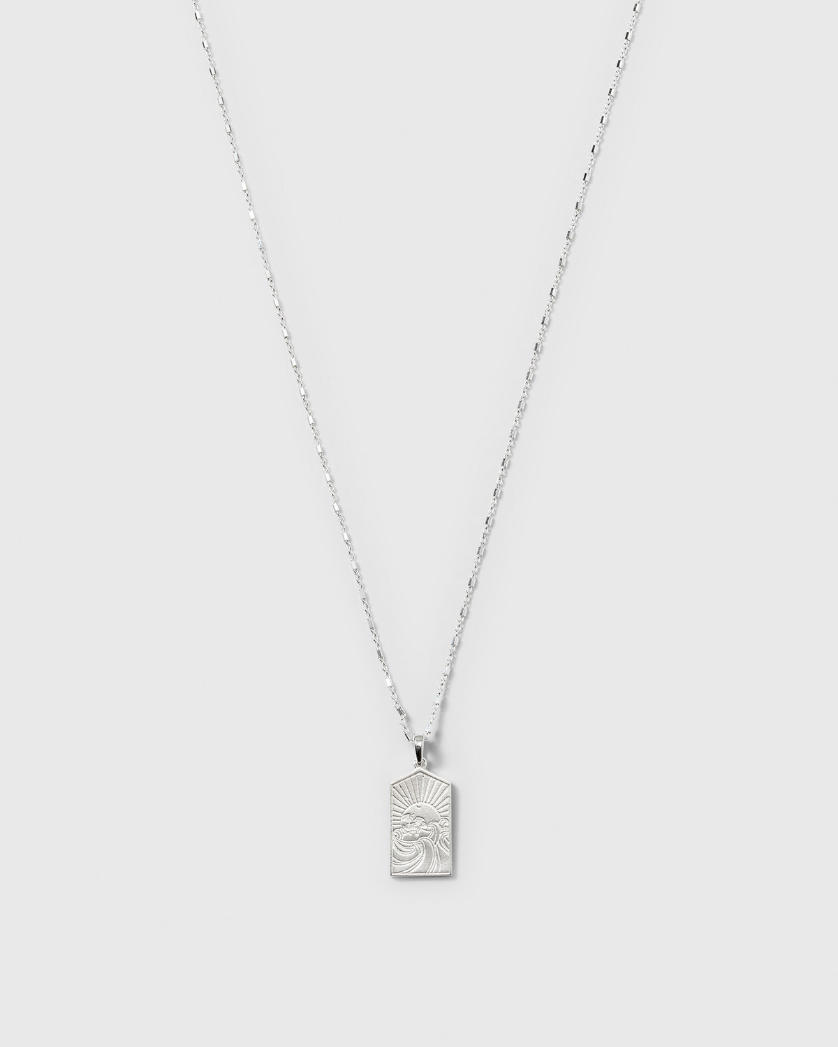 A product shot of the Lucky Coin Keep Dreaming Necklace in silver, showcasing its fine chain and rectangular pendant engraved with a sun and waves design.