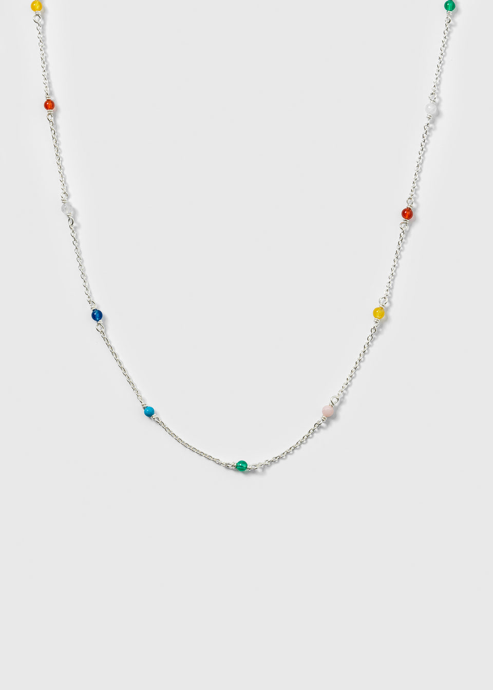 A product shot of the Santa Monica Necklace in silver, laid out to display its design of a fine chain adorned with small, colorful gemstone beads: Yellow Jade, Pink Opal, Sodalite, Green Onyx, Blue Color Reconstituted Turquoise, White Agate, and Carnelian