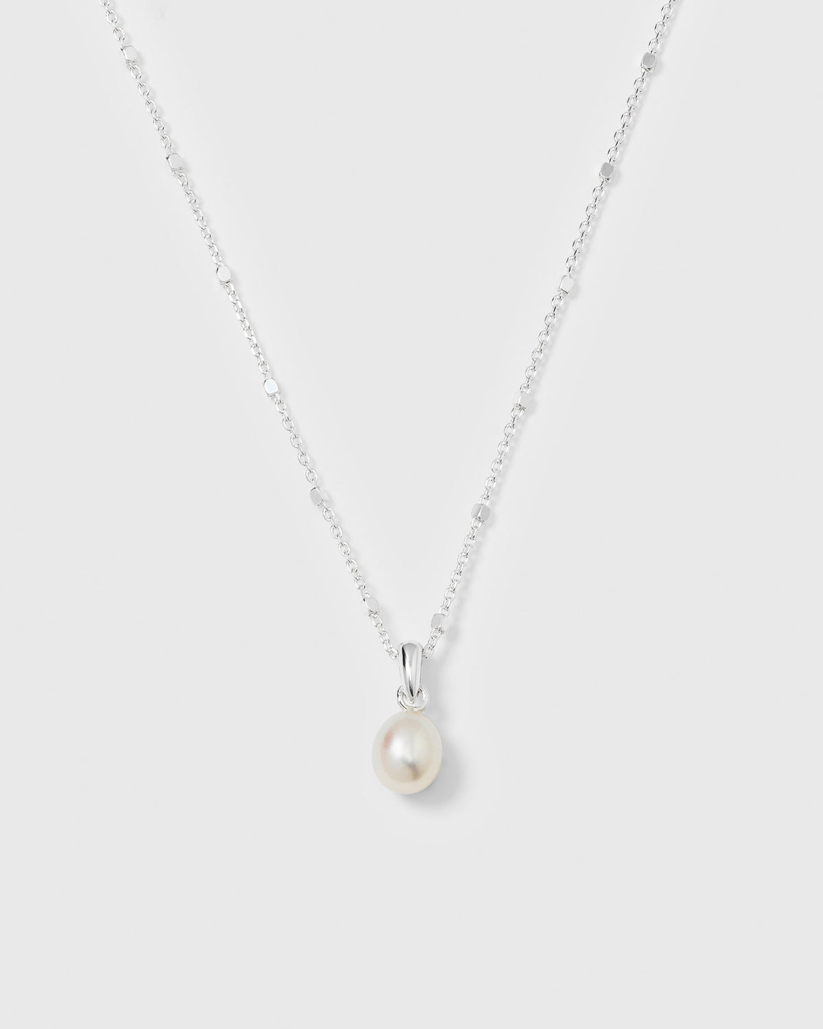 A product shot of the Treasure Single Pearl Necklace in silver, featuring its delicate chain design and a single teardrop-shaped freshwater pearl pendant.