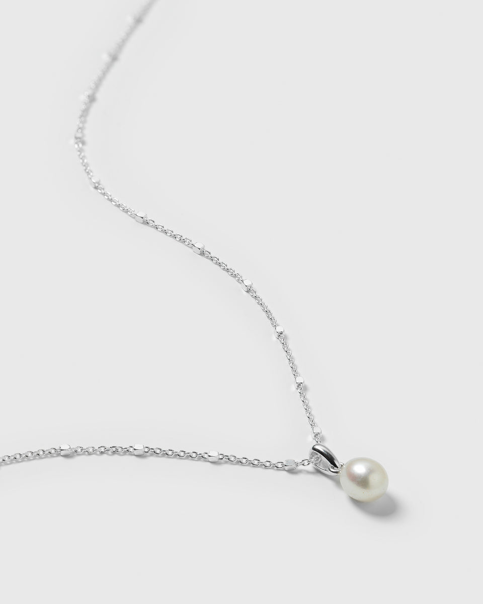 A close-up image of the silver Treasure Single Pearl Necklace, detailing its delicate chain and single teardrop freshwater pearl.