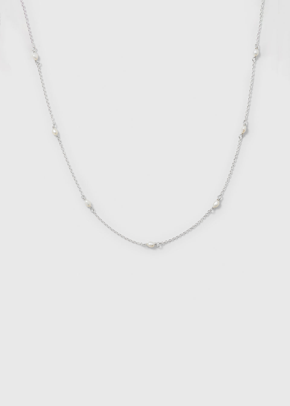 A product shot of the Treasure Multi Pearl Necklace in silver, showcasing its fine chain design with multiple small freshwater pearls spaced along it.