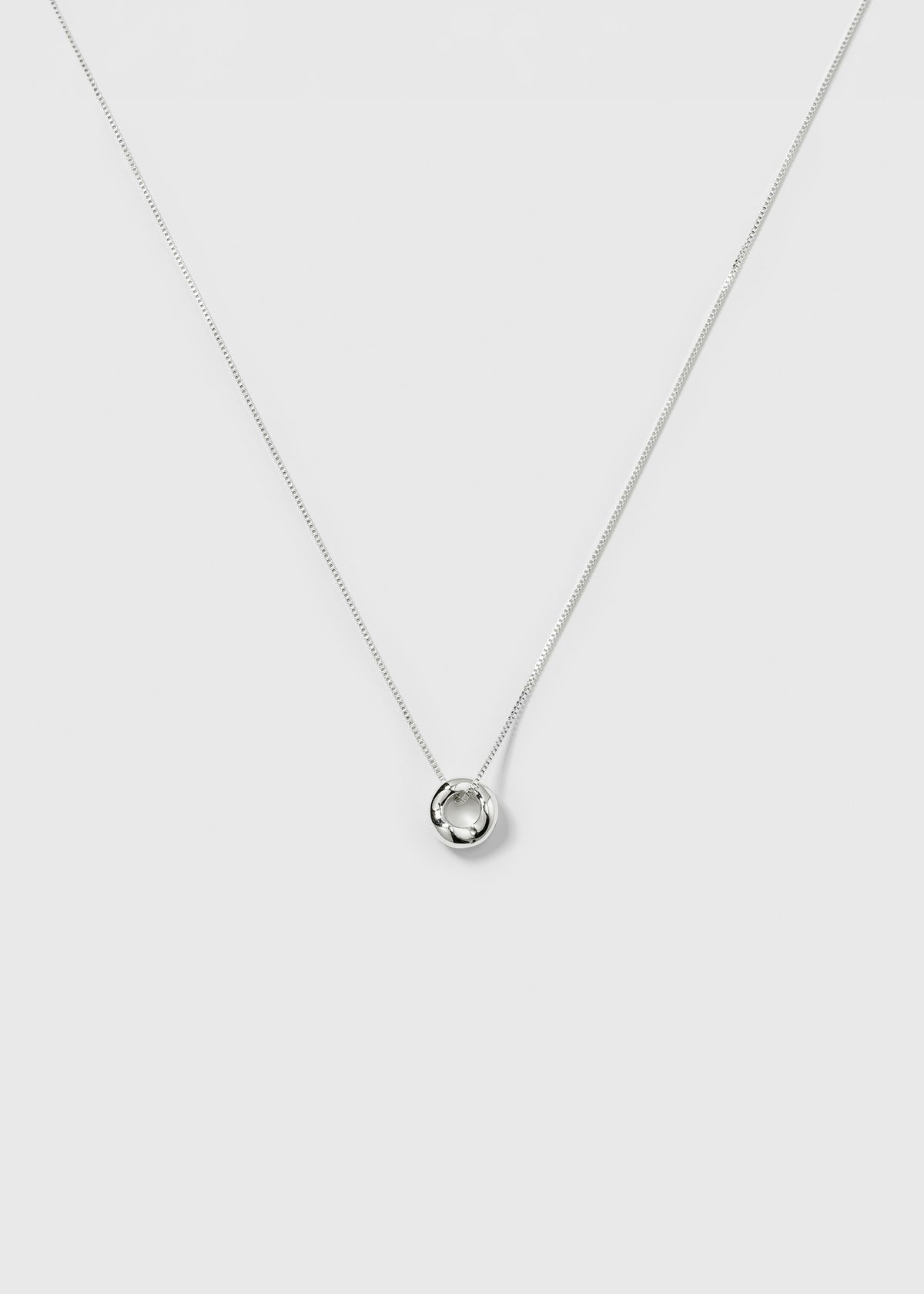 A product shot of the Bolded Wavy Necklace in silver, featuring a smooth chain and a shiny pendant with a wavy, circular design.