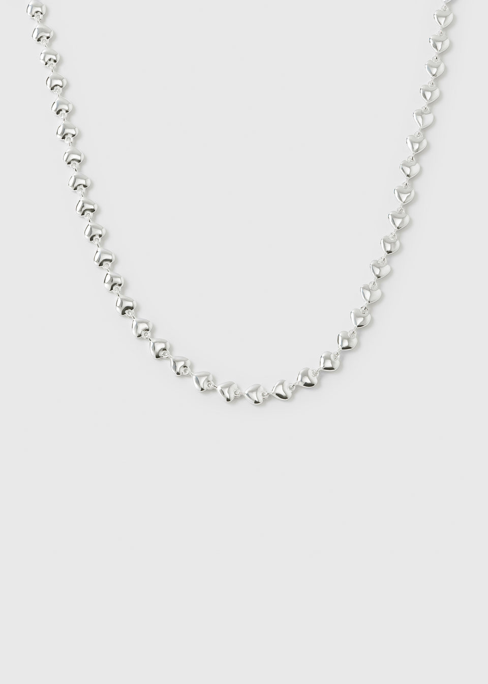 A product shot of the Darling Necklace in silver, displaying its chain made of small, interconnected hearts.