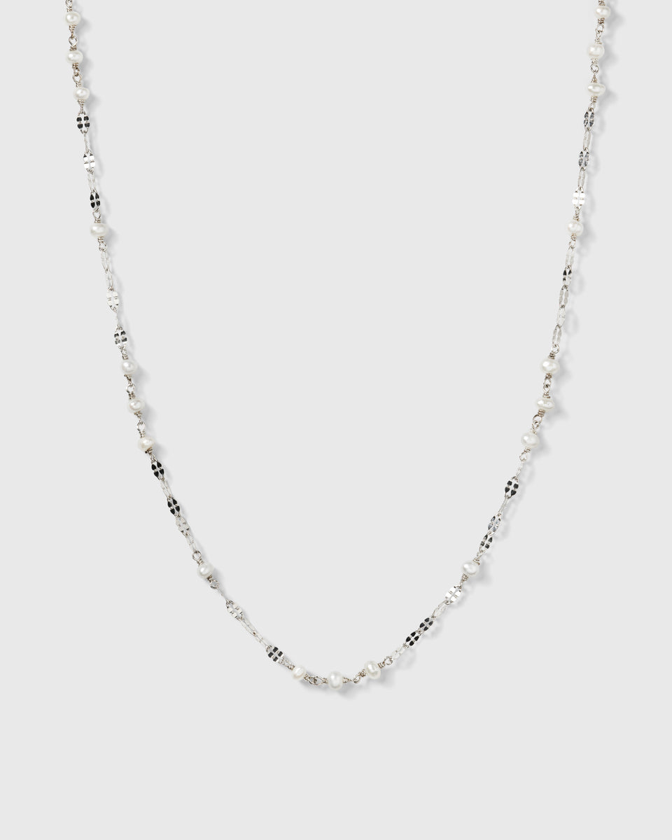 A product shot of the Aurelia Necklace in silver, laid out to showcase its unique chain design interspersed with small freshwater pearls.