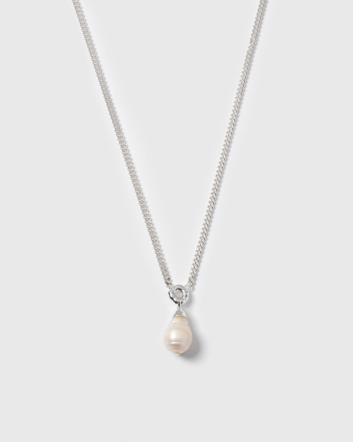 A product shot of the Mary Necklace in silver, featuring a heavy chain and a unique teardrop-shaped baroque pearl pendant.