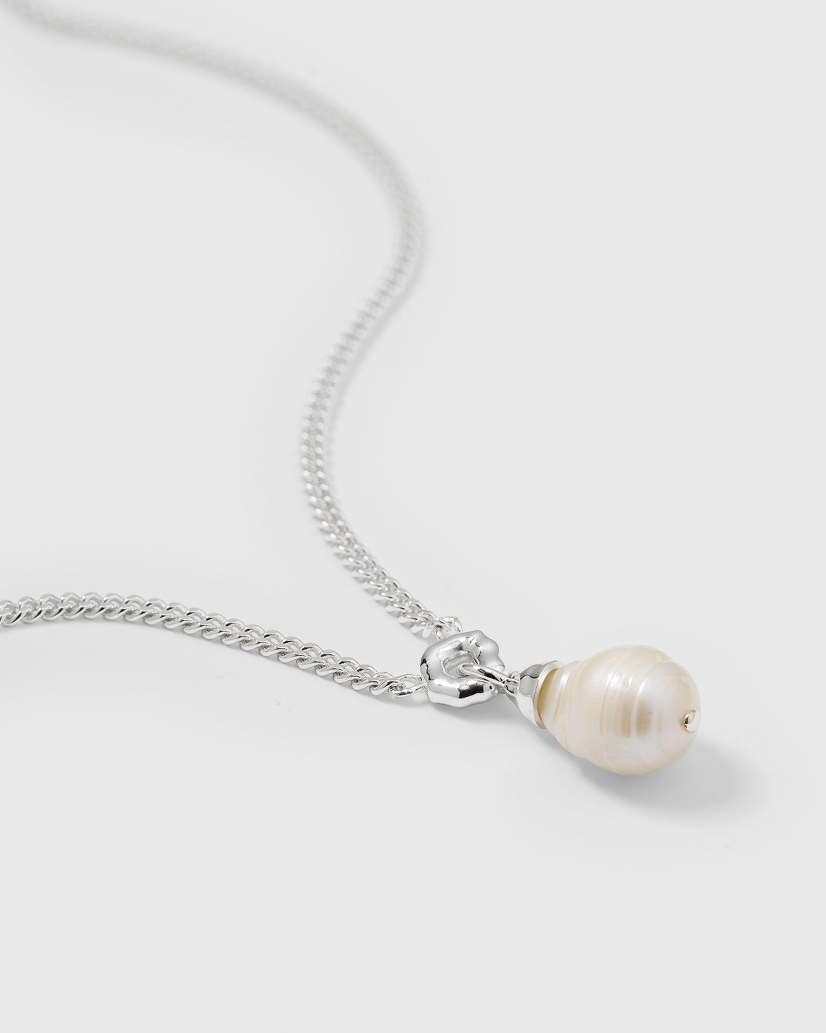 A close-up product shot of the Mary Necklace Silver, focusing on its heavy sterling silver chain and unique baroque pearl pendant.