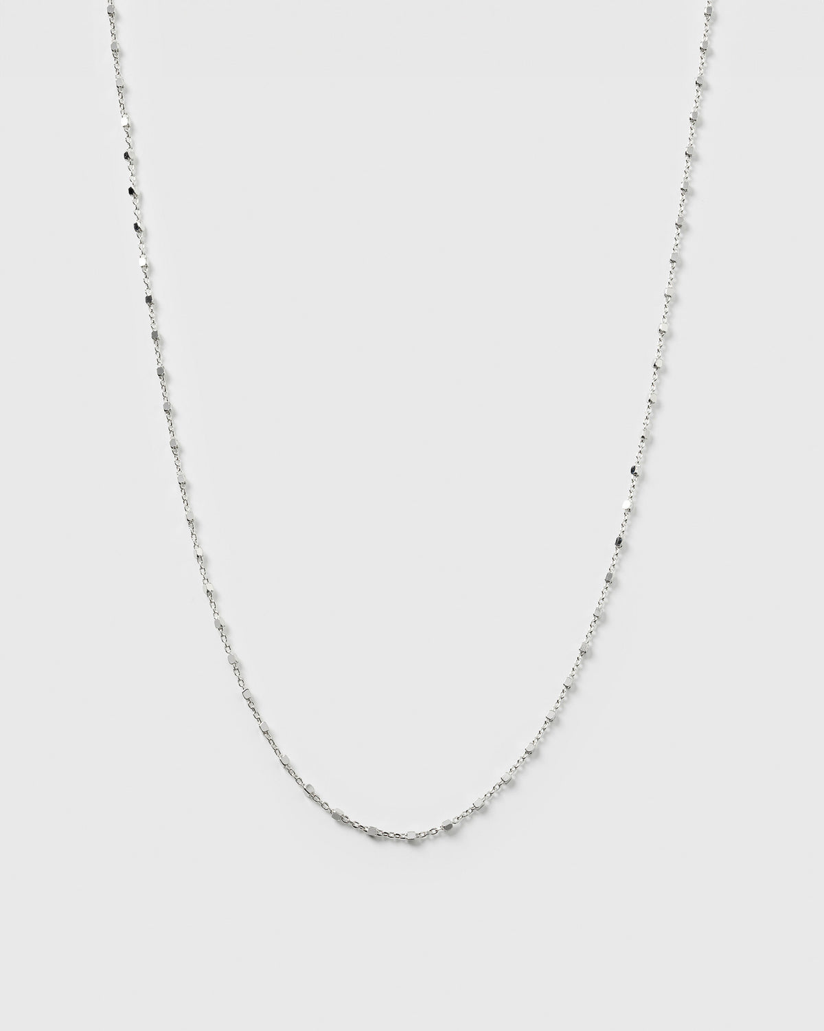 A product shot of the Sheer Station Necklace in silver, featuring a delicate chain with tiny, shining dots spaced along its length.