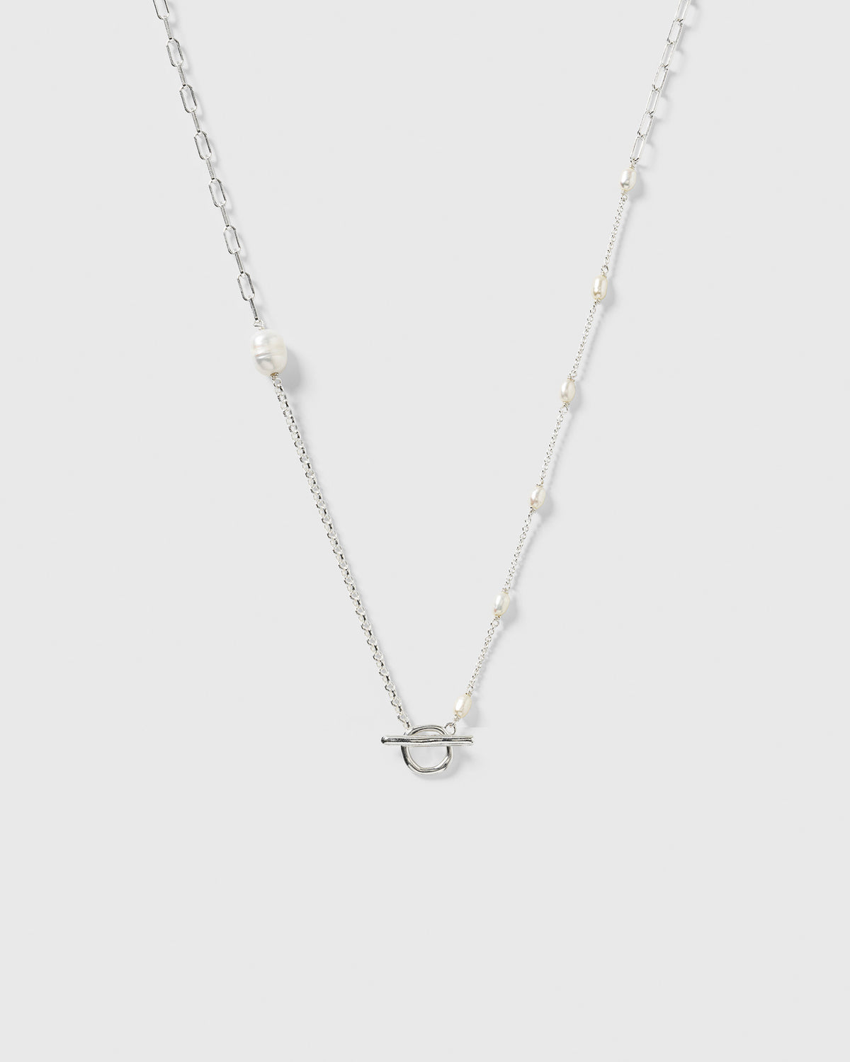 The Paxton Short Necklace made from recycled sterling silver, featuring a mix of three chain link styles, unique baroque freshwater pearls, and a toggle clasp.