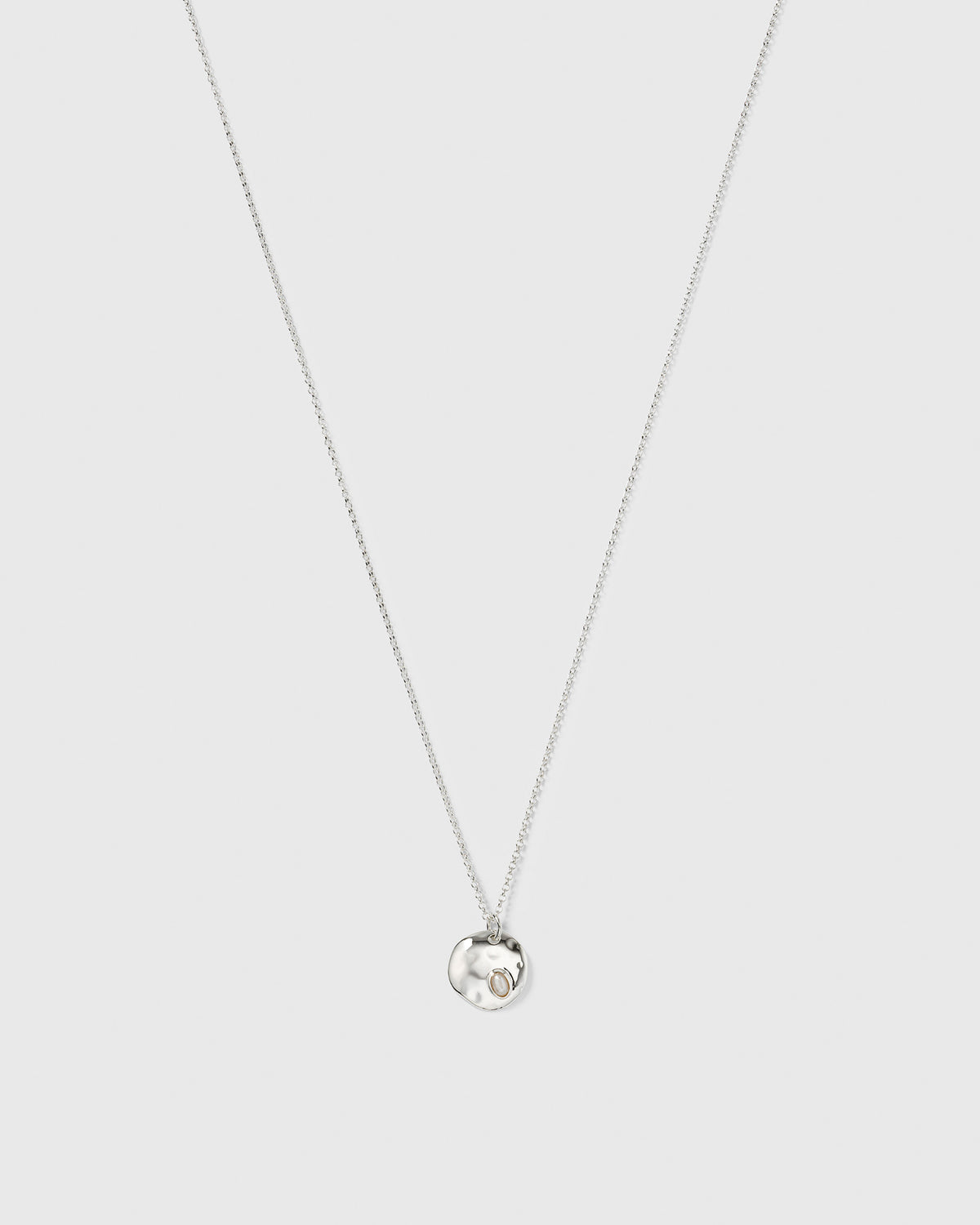 Paxton silver necklace with a fine chain and a hammered pendant holding a baroque freshwater pearl.
