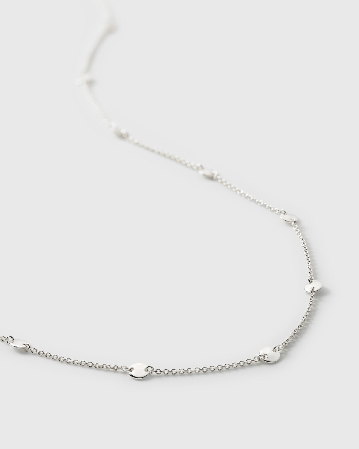 A close-up image of the Solea Necklace in silver, detailing the fine chain and the small, hammered, round circles spaced along it.