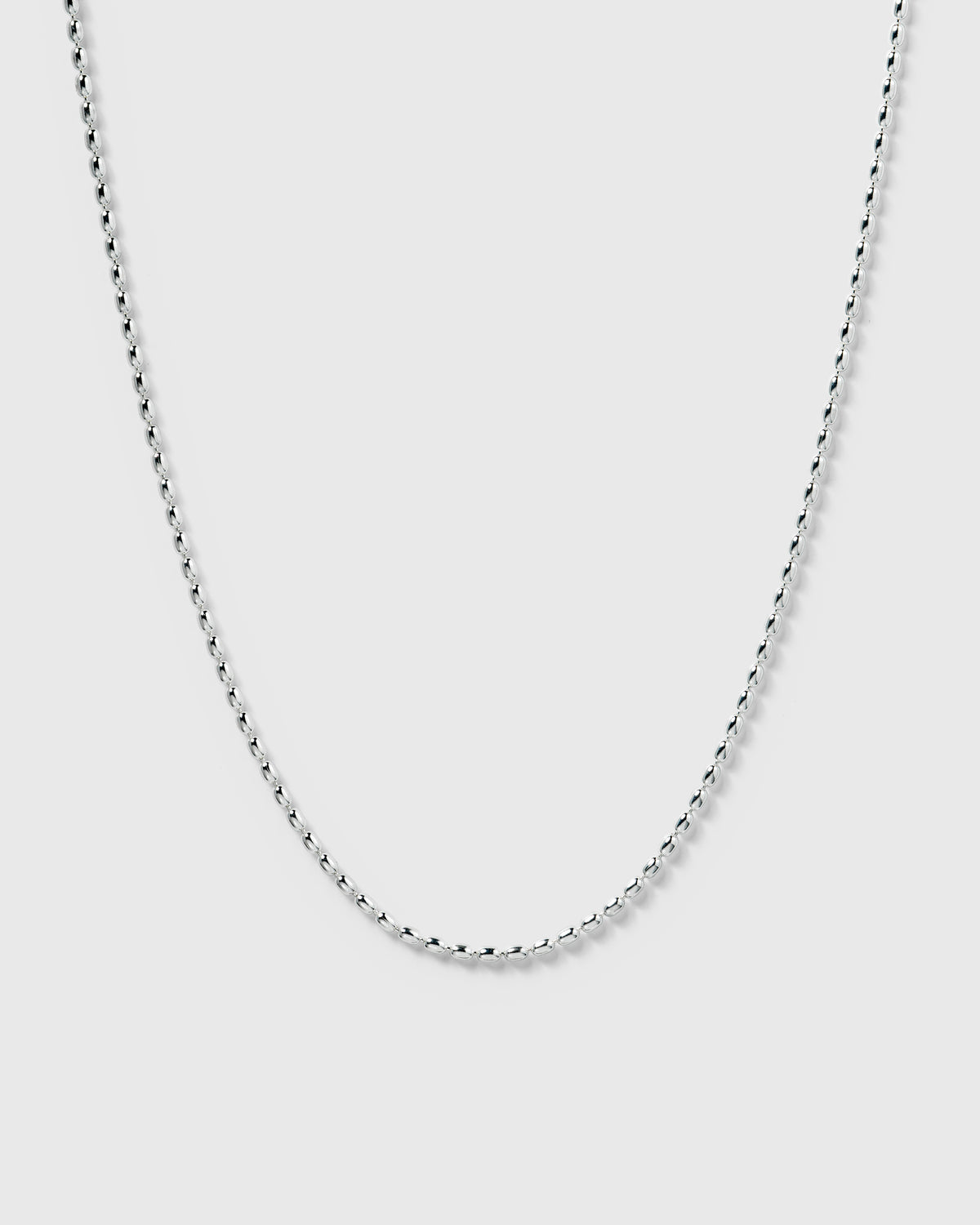 A product shot of the Lunetta Necklace in silver, part of a set, showcasing its delicate chain made of small, shiny, oval-shaped links.