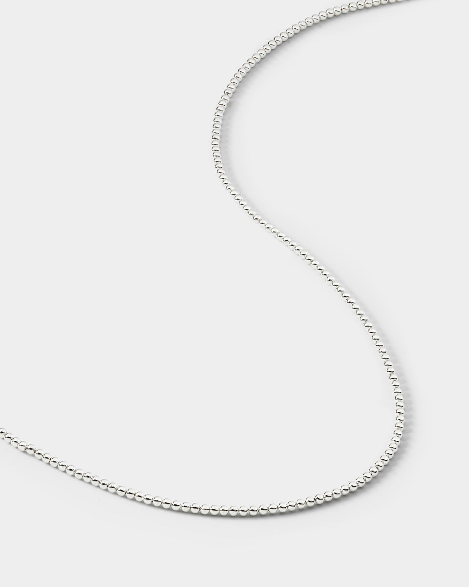 A close-up product shot of the Sheer Doria Necklace in silver, showing the delicate chain made of small, polished sterling silver beads.