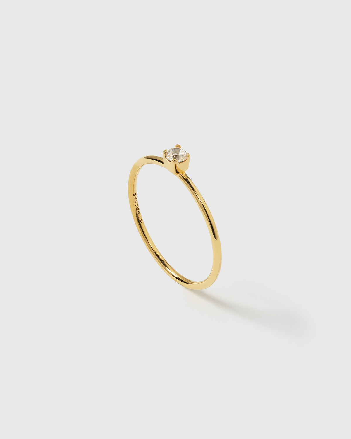 A product shot of the Tiny Princess Ring Gold, highlighting its delicate, thin band and a single, sparkling crystal in a princess setting.