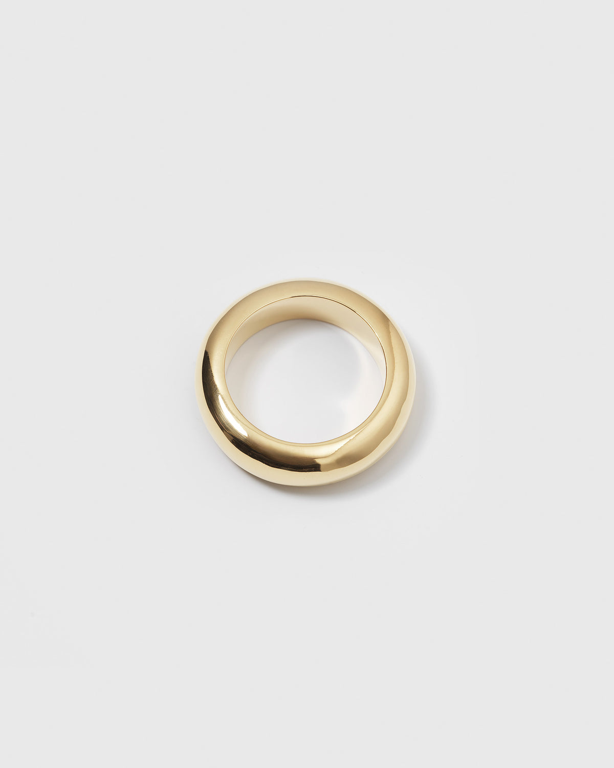 A product shot of the Bolded Ring in gold, laid flat to showcase its chunky, smooth, and rounded band design.