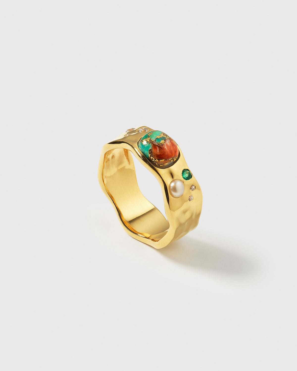A product shot of the Melting Ring in gold, showcasing its organic, melted design. The ring is adorned with an irregular setting of gemstones, including a large oyster turquoise, a freshwater pearl, green aventurine, and tiny zirconias.