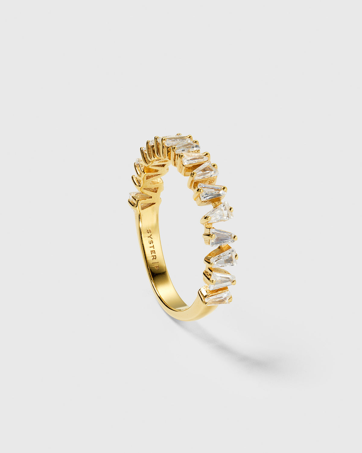 A product shot of the Iggy Ring in gold, featuring its unique band adorned with tapered baguette-cut cubic zirconias.
