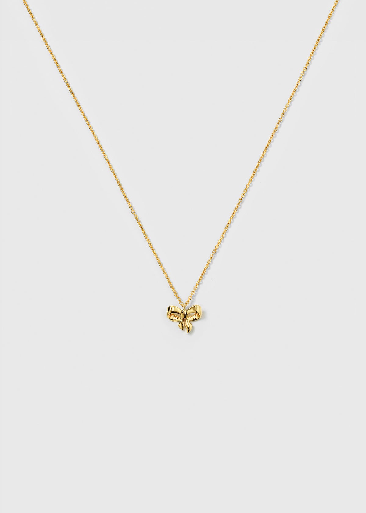 A product shot of the Rosie Mini Necklace in gold, featuring a delicate bow-shaped pendant on a sparkling, fine-linked chain.