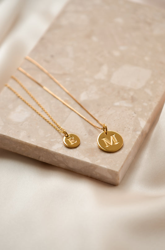 Gold necklace with small letter pendant next to necklace with big letter pendant 