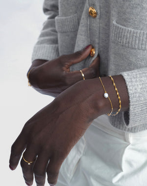 Two bracelets styled together, one with a fresh water pearl and one with a twisted chain