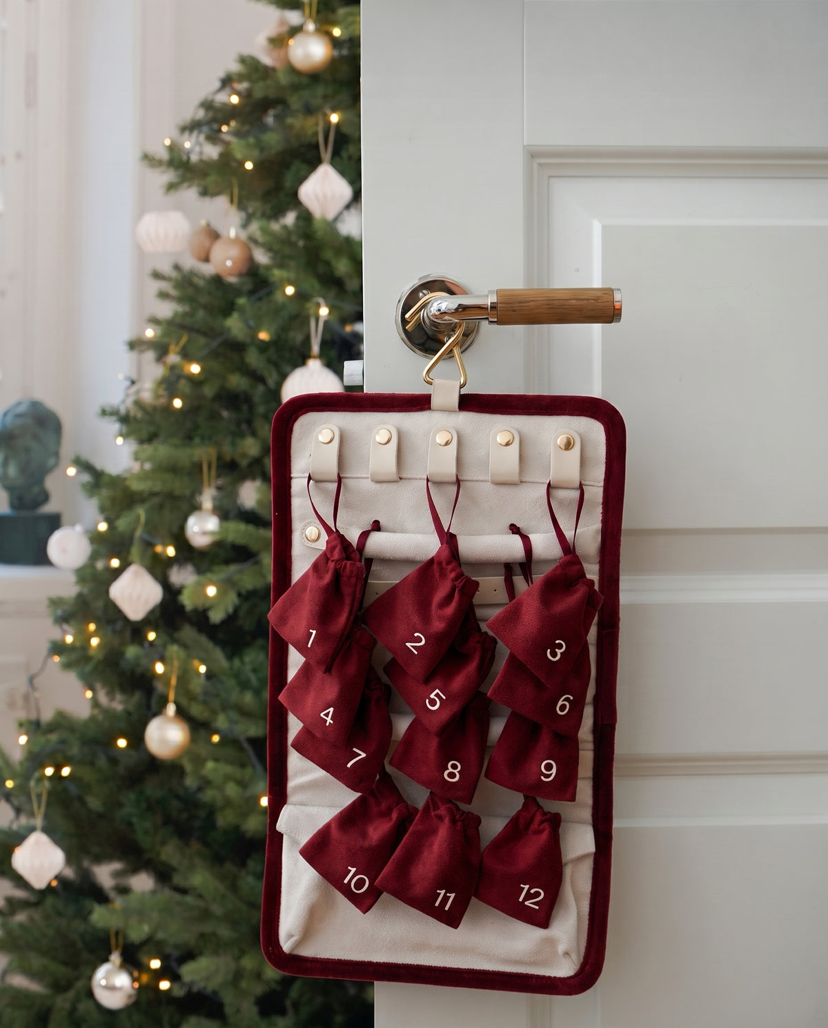 A lifestyle image of the Syster P Advent Calendar hanging on a door, showcasing the 12 doors