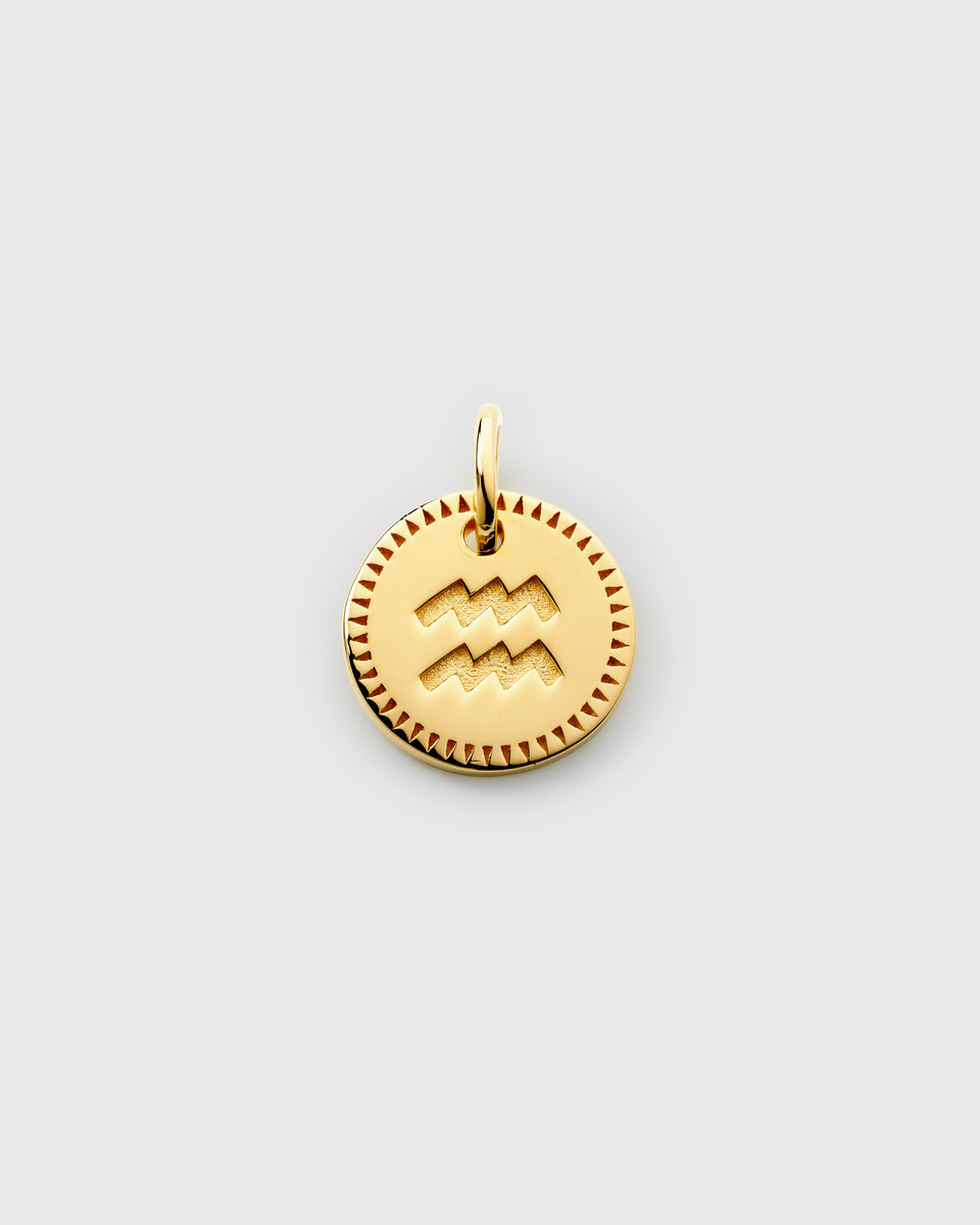 A product shot of the Beloved Zodie Pendant Gold for the star sign Aquarius, featuring the zodiac symbol engraved on a round charm with a decorative, patterned border.