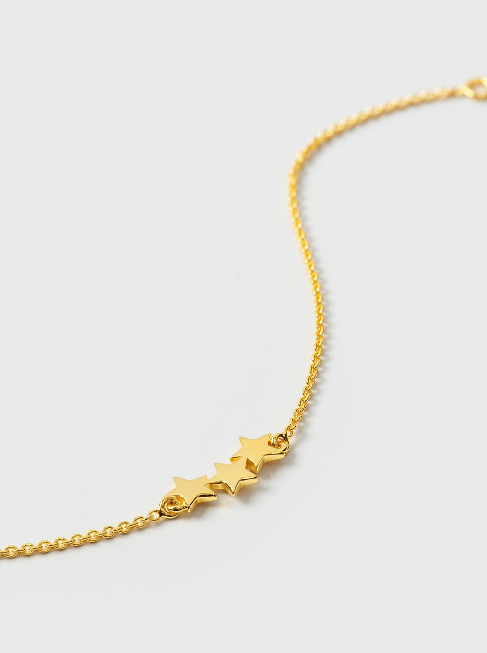 A product shot of the Snap Triple Star Bracelet in gold, focusing on the three star charms on its delicate box chain.