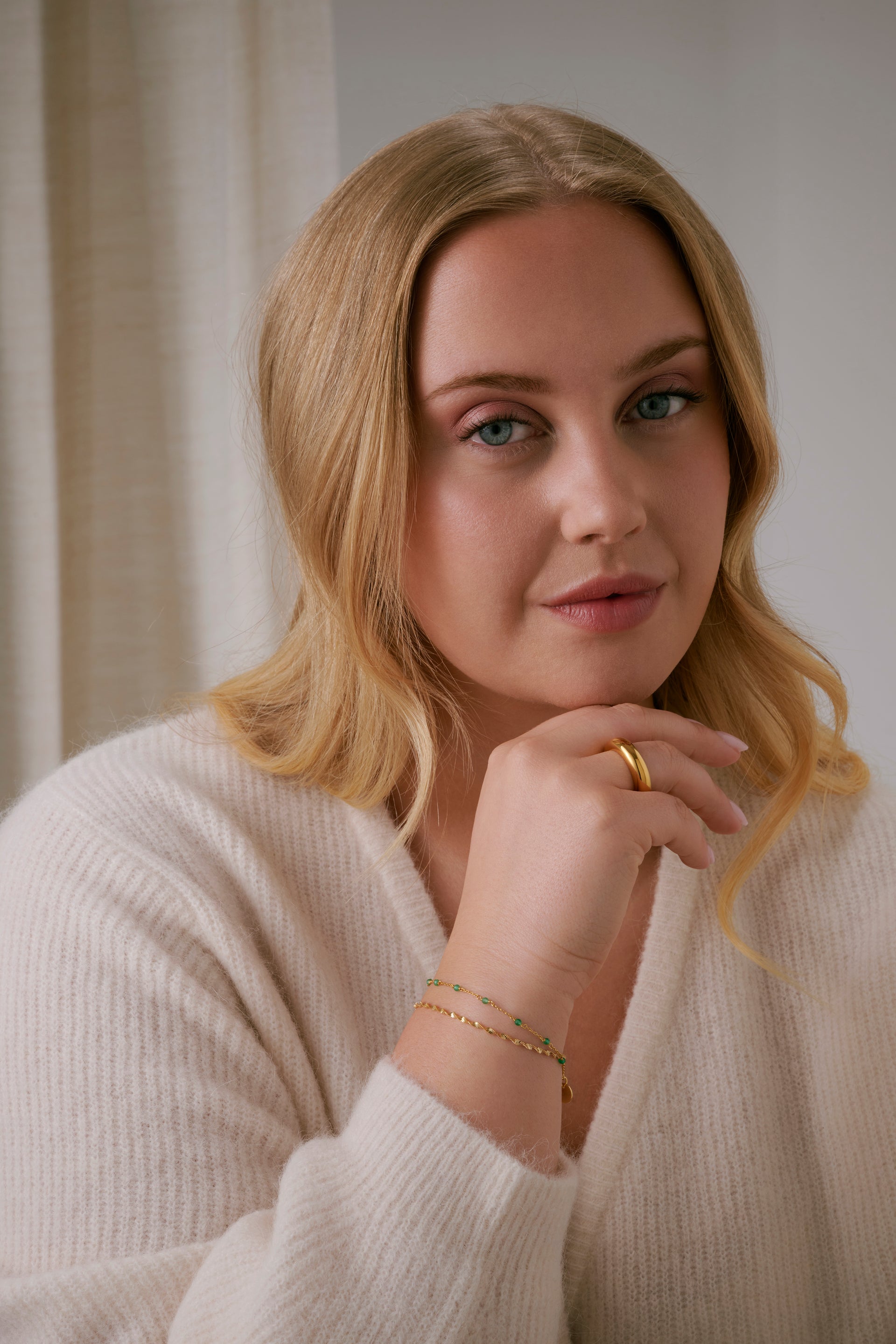 A shot of a model's showcasing the Santa Monica Bracelet in gold with green onyx stones spaced throughout, layered with a twisted bracelet and paired with a chunky gold ring.