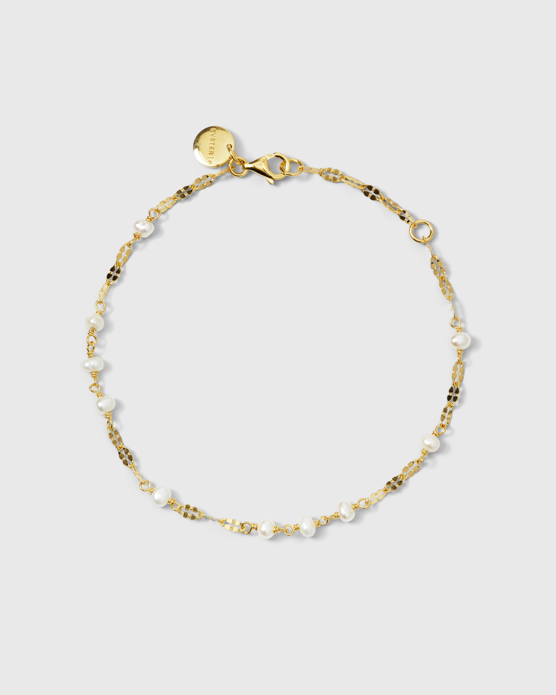 A product shot of the Aurelia Bracelet in gold, laid out in a circle to display its design of a fine, decorative chain interspersed with small freshwater pearls.