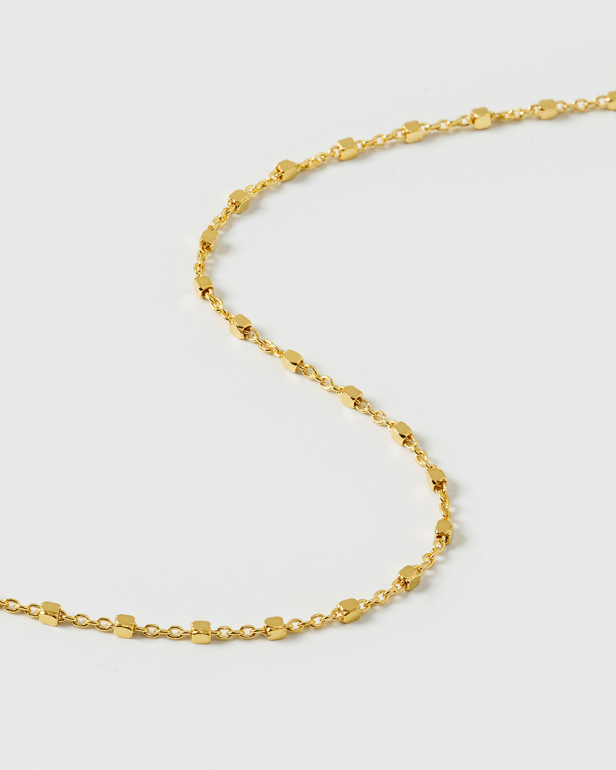 A close-up shot of the Sheer Station Bracelet in gold, showcasing its delicate station chain design with tiny, shining dots.