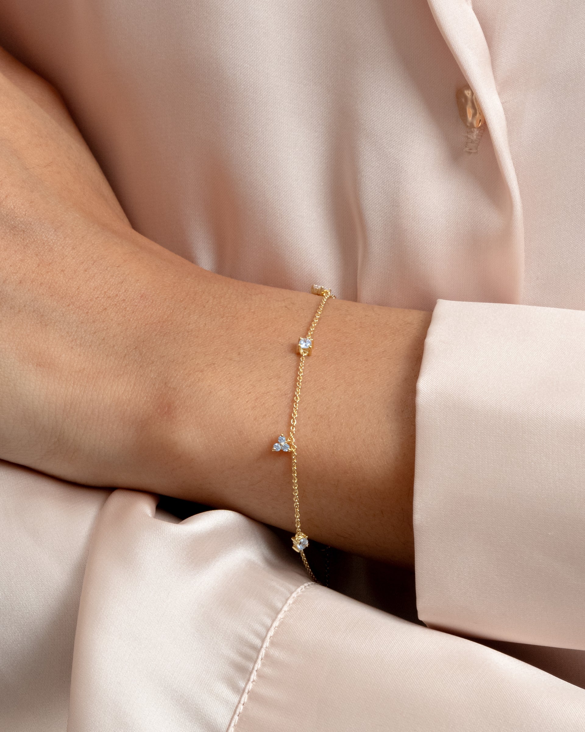 A close-up shot of a model wearing the Celestia Bracelet in gold, showcasing its delicate chain adorned with sparkling cubic zirconias.