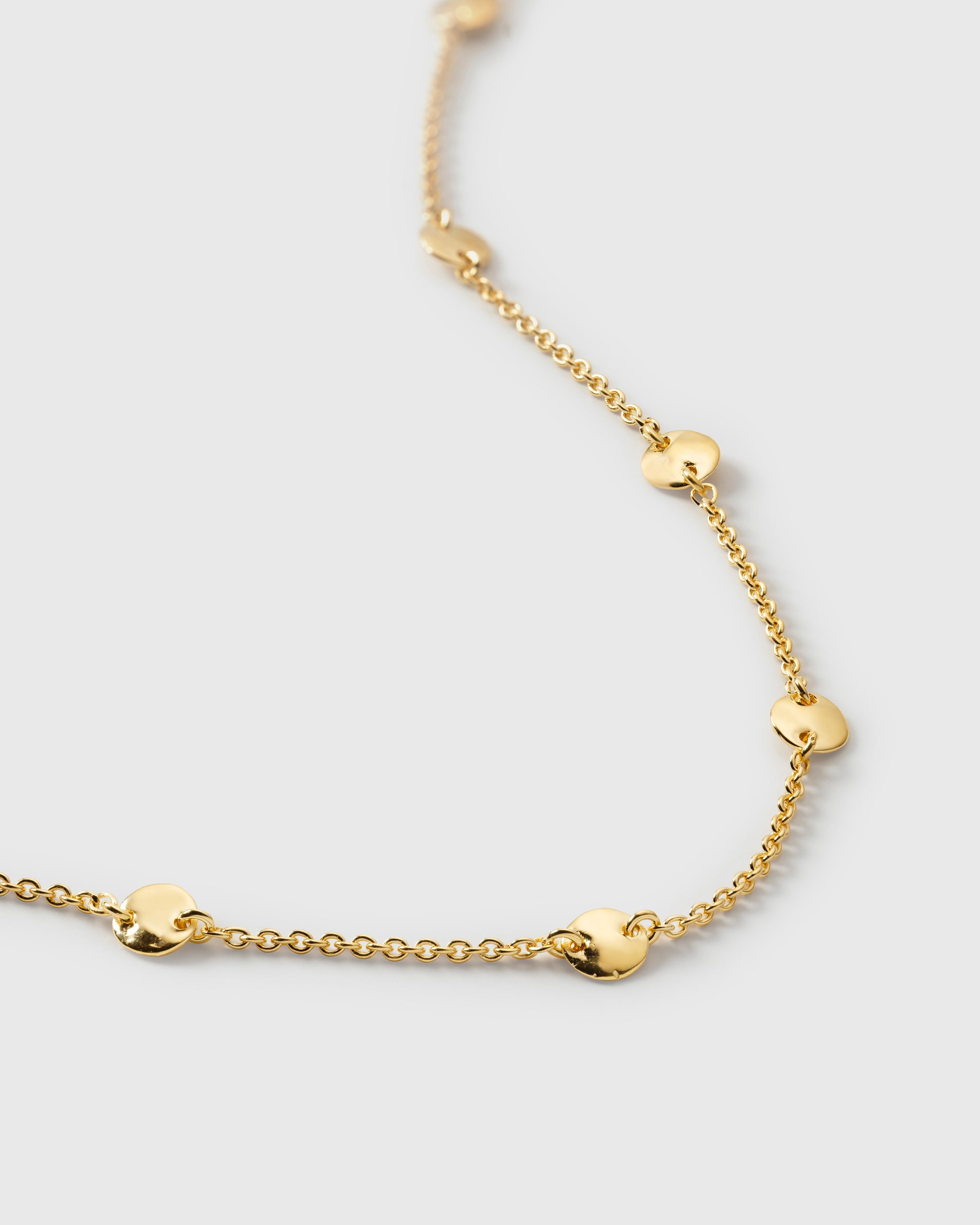 A close-up of the Solea Bracelet in gold, showing its delicate chain decorated with small, round hammered circles.