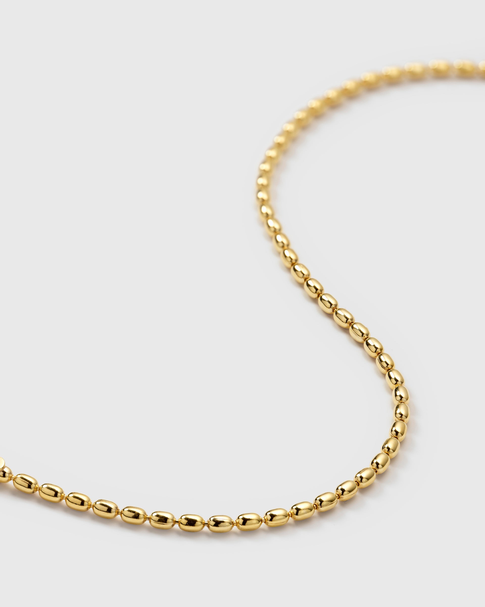 A close-up product shot of the Lunetta Bracelet in gold, showcasing its unique ball chain design composed of small, oval beads.