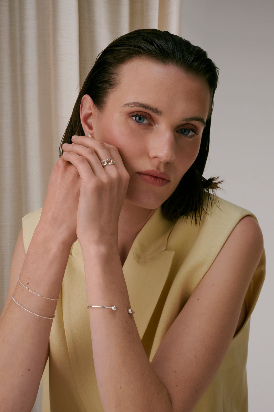 Silver open ball bangle layered with two delicate silver chain bracelets, paired with a silver chain link ring.