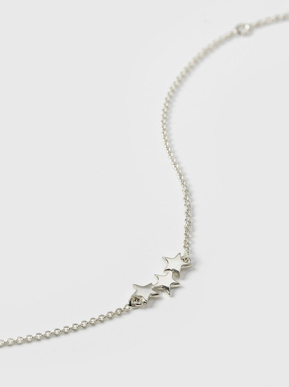 A close-up product shot of the Snap Triple Star Bracelet in silver, highlighting the detail of the three star charms attached to the delicate box chain.