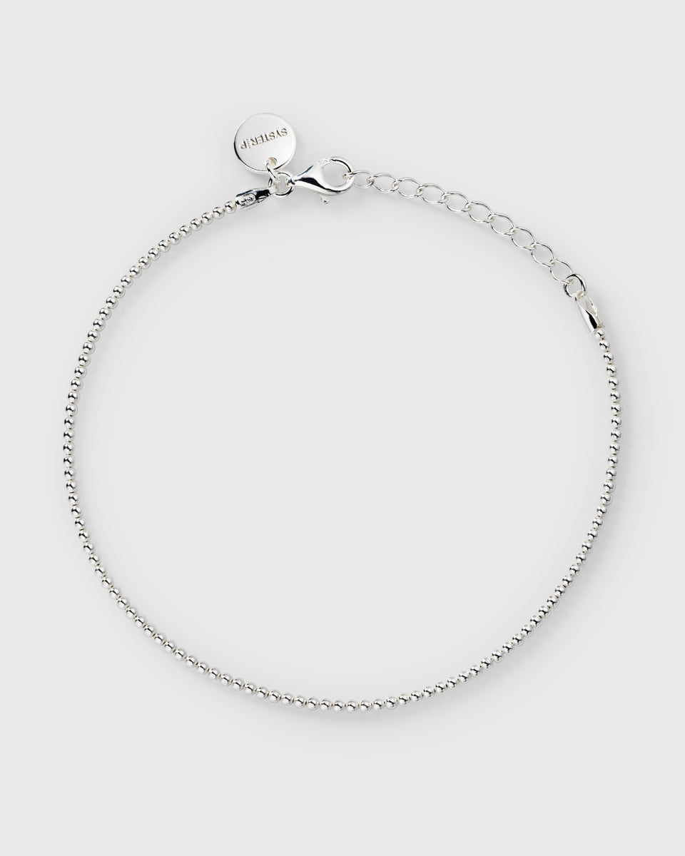 A product shot of the Syster P Sheer Doria Bracelet in silver, a delicate ball chain bracelet with an adjustable lobster clasp and a small branded charm.