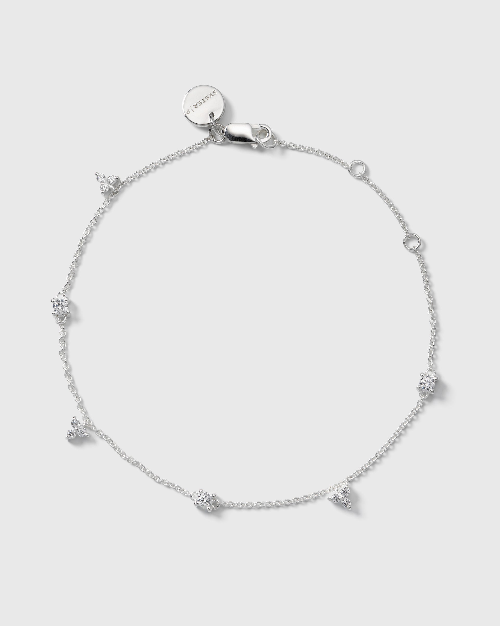A product shot of the Celestia Bracelet in silver, laid out in a circle to display its delicate chain adorned with clusters of sparkling cubic zirconias.