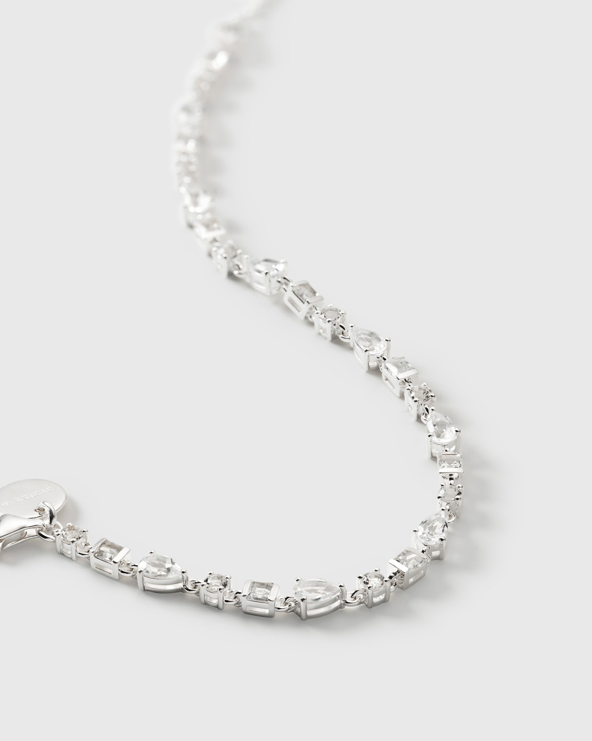 A close-up product shot of the Pam Bracelet in silver, highlighting its intricate design featuring various shapes of sparkling white topaz stones.